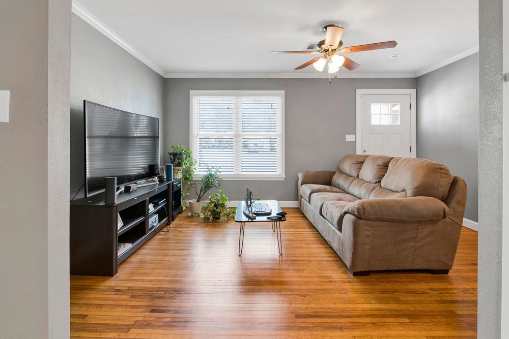 This image showcases a bright and cozy living room with hardwood floors and a neutral color palette. The space features a large window that allows for plenty of natural light,