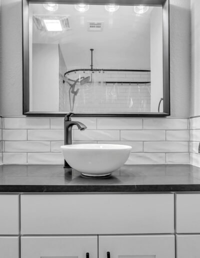 At the center sits a contemporary vessel sink—smooth, round, and minimalist—paired with a matte black faucet that adds a touch of sophistication.